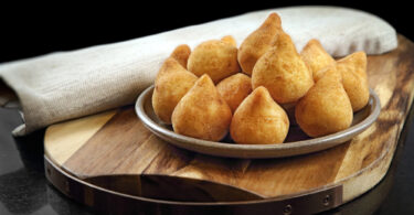 Uma travessa cheia de cozinhas. Coxinha.