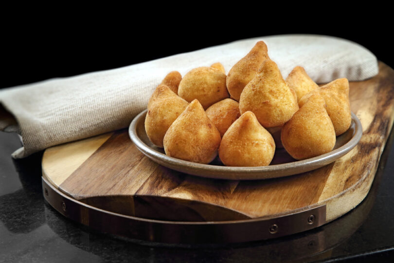 Uma travessa cheia de cozinhas. Coxinha.