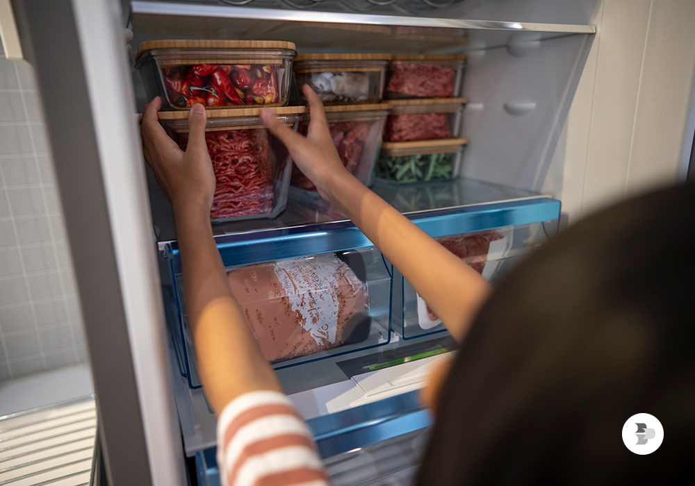 Uma moça organizando os alimentos em sua geladeira. Limpa geladeira.