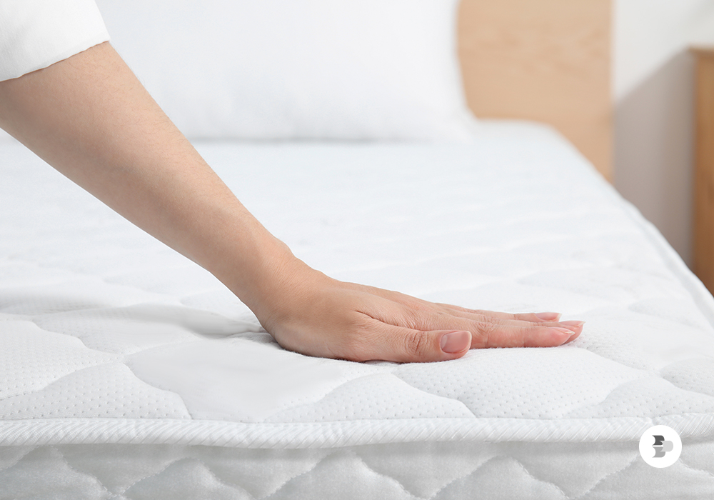 Pessoa testando a maciez do seu colchão. Melhor colchão.