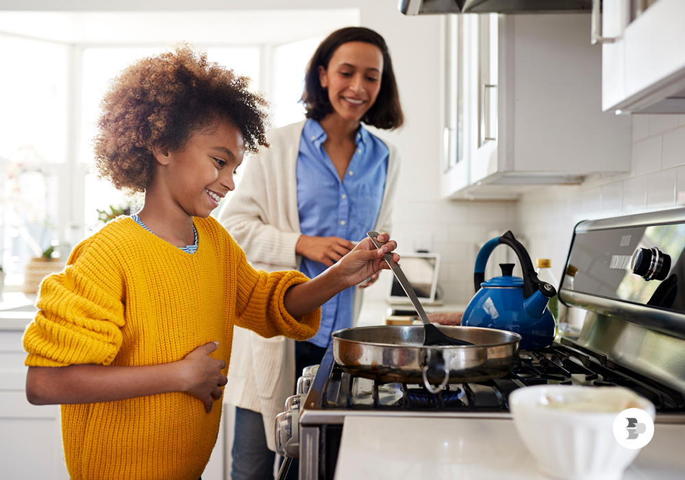 Uma mãe ensinando seu filho a cozinhar. Fogão cooktop.