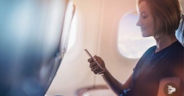 Uma mulher utilizando o whatsaap offline dentro de um avião. Whatsapp offline.