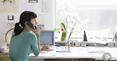 Uma moça atendendo uma ligação enquanto trabalha em casa. Escritório.