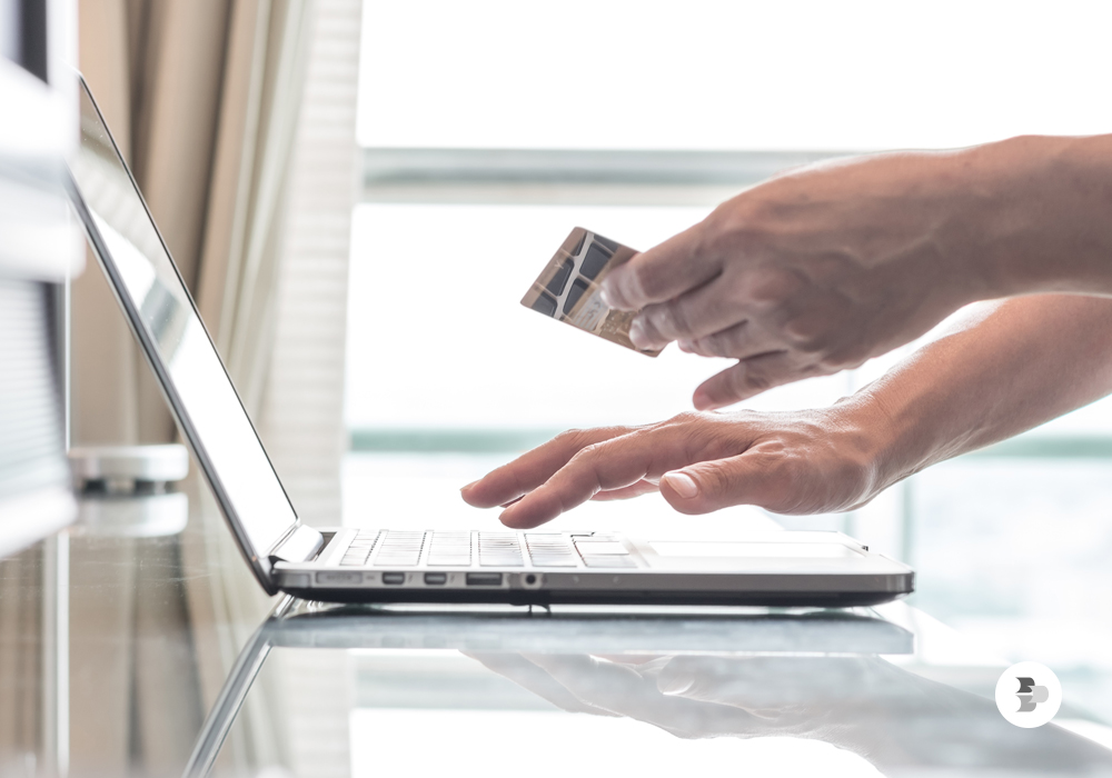 Pessoa com cartão de crédito comprando através de um notebook.