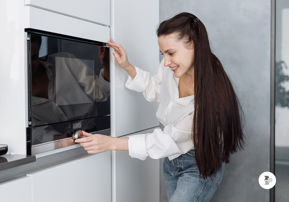 Uma moça utilizando o seu micro-ondas em casa. Melhor micro-ondas