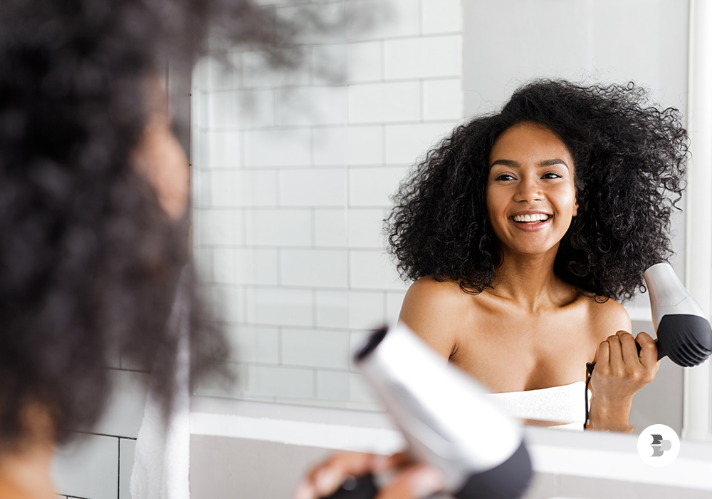 Jovem secando os seus cabelos com a secadora. Cabelo inverno.