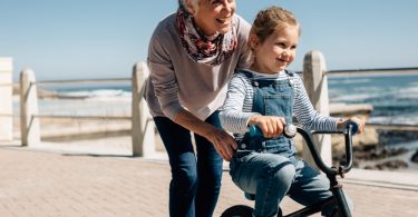 senior woman helping her granddaughter learn to ride a bicycle picture id1220309046