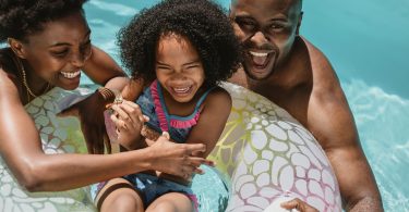 Uma família aproveitando o dia para nadar na piscina. Verão.