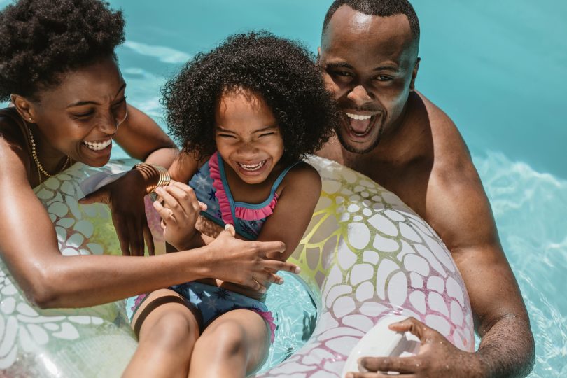 Uma família aproveitando o dia para nadar na piscina. Verão.