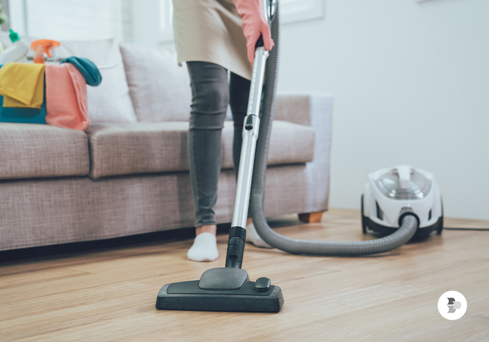 Pessoa aspirando o tapete da sua casa. Aspirador de pó.