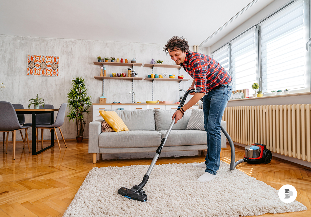 Uma mulher aspirando o tapete com aspirador convencional. Aspirador de pó.
