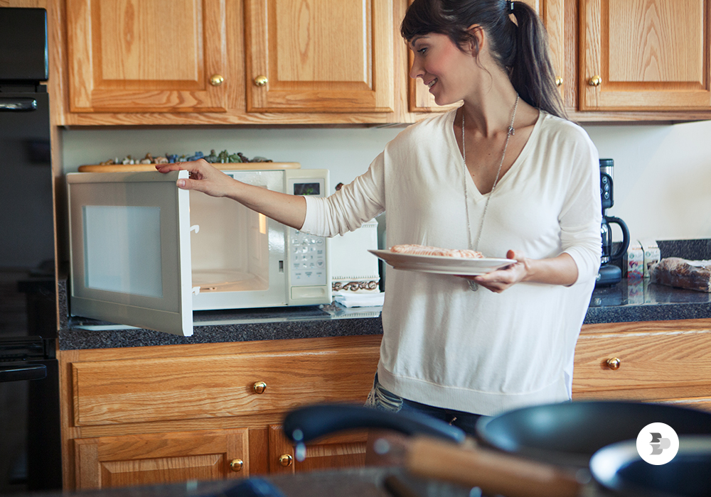 Mulher utilizando um Micro-Ondas convencional. Micro-Ondas.