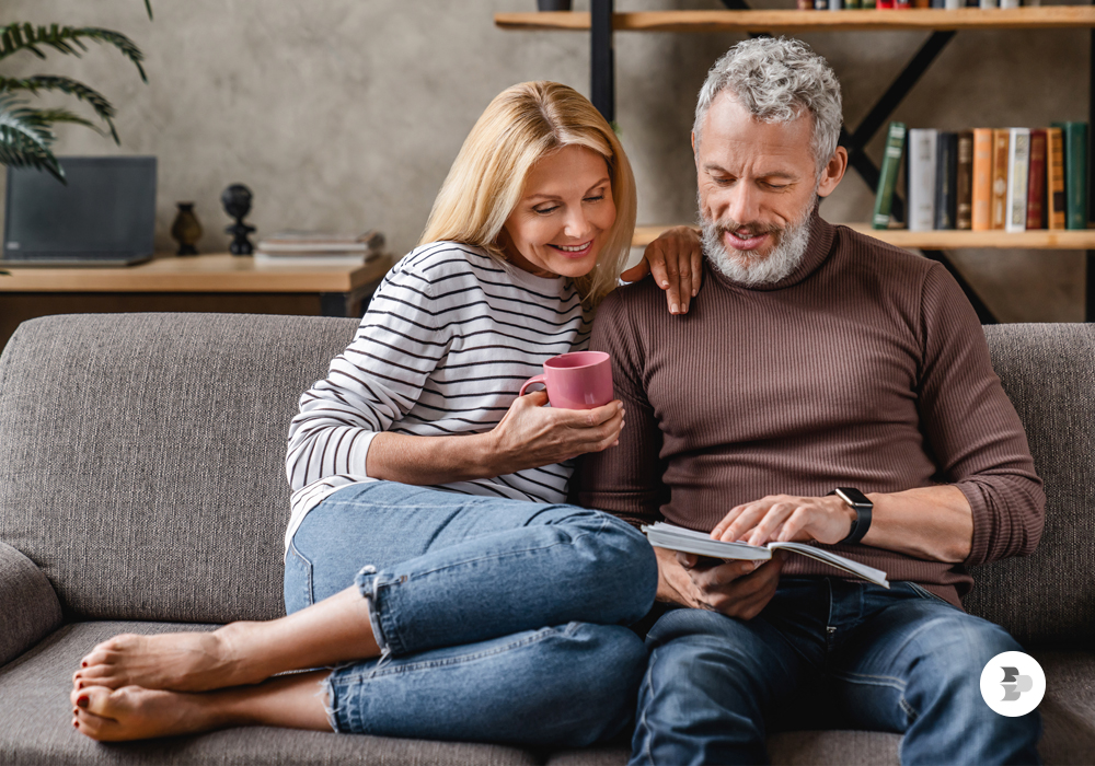 Casal sentados juntos no sofá e lendo um dos melhores livros para ler sobre a vida.