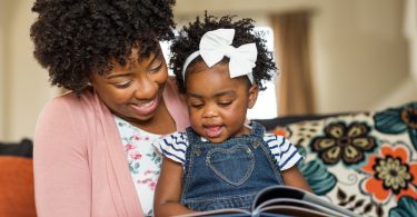 Mãe contando uma historinha para a sua filha. Livros infantis.