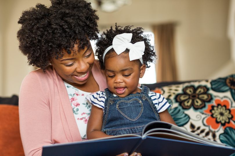 Mãe contando uma historinha para a sua filha. Livros infantis.