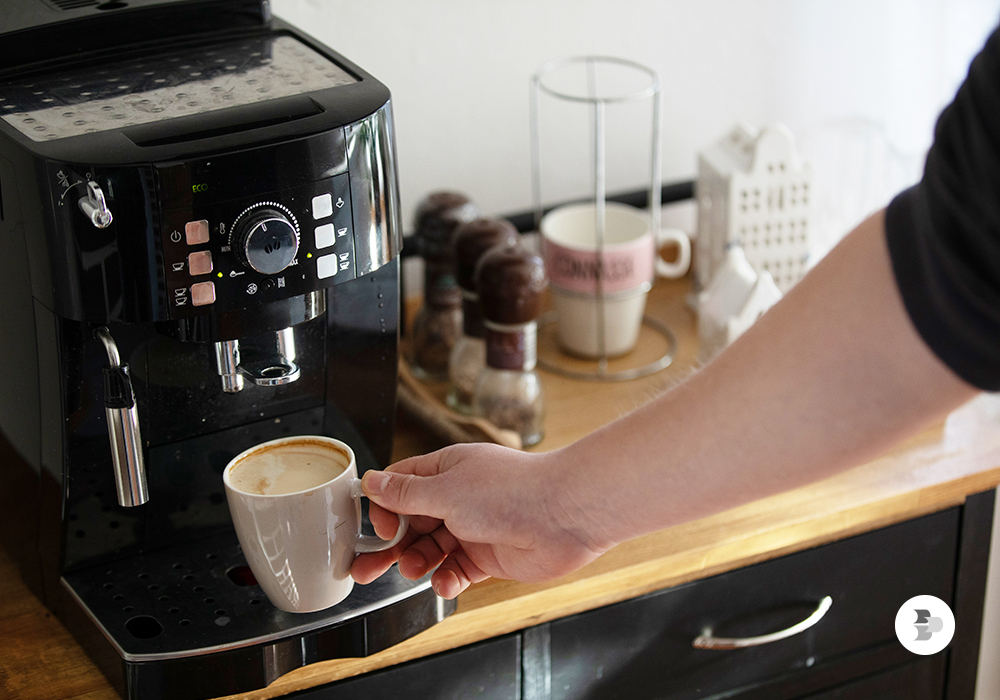Pessoa se servindo um pouco de café no espaço que ela criou. Cantinho do café.