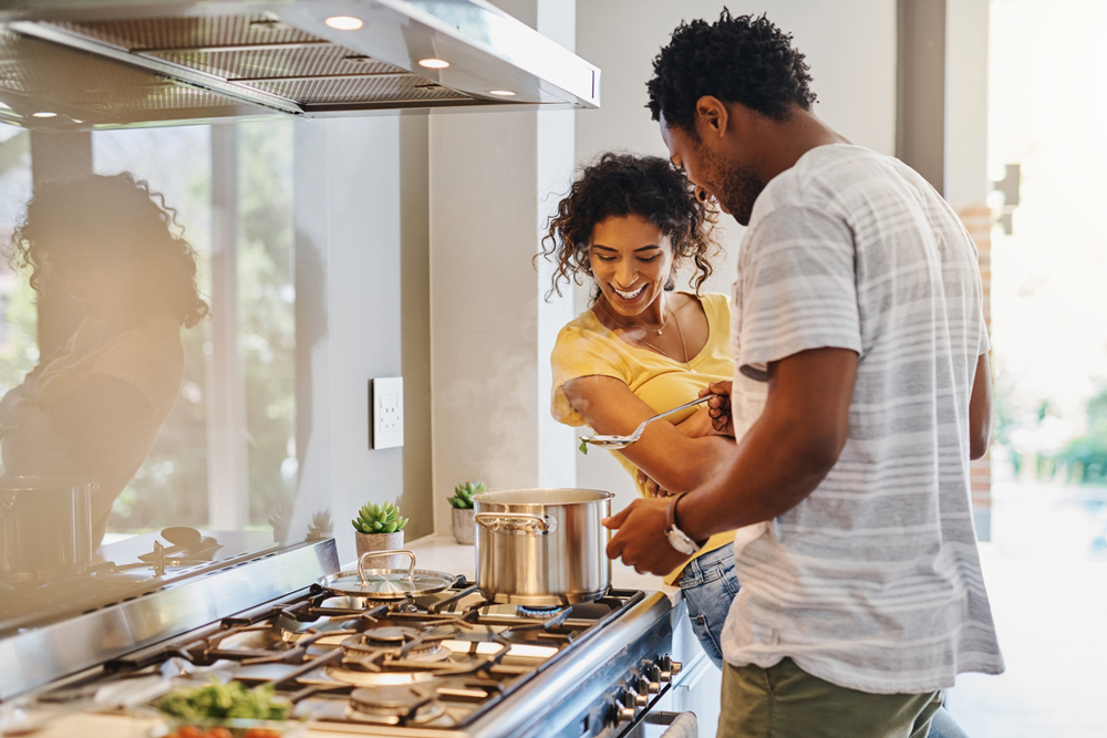 Marido e esposa cozinhando juntos em um fogão. Fogão de cozinha.