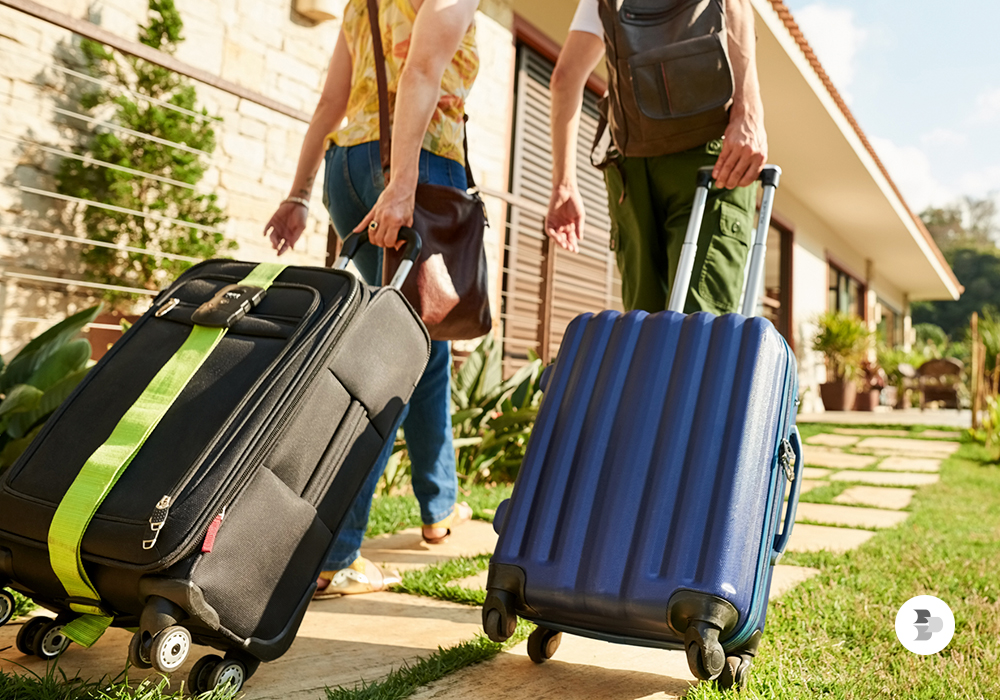 Um casal chegando em um hotel com as suas malas. Malas viagem.