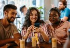 Um trio de jovens usando um smartphone. Black Friday Smartphone Celular.