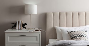 Uma mesa de cabeceira com abajur em cima. Mesa de cabeceira.