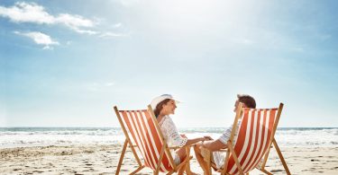 Um casal sentado em suas cadeiras de praia na areia. Cadeira de praia.