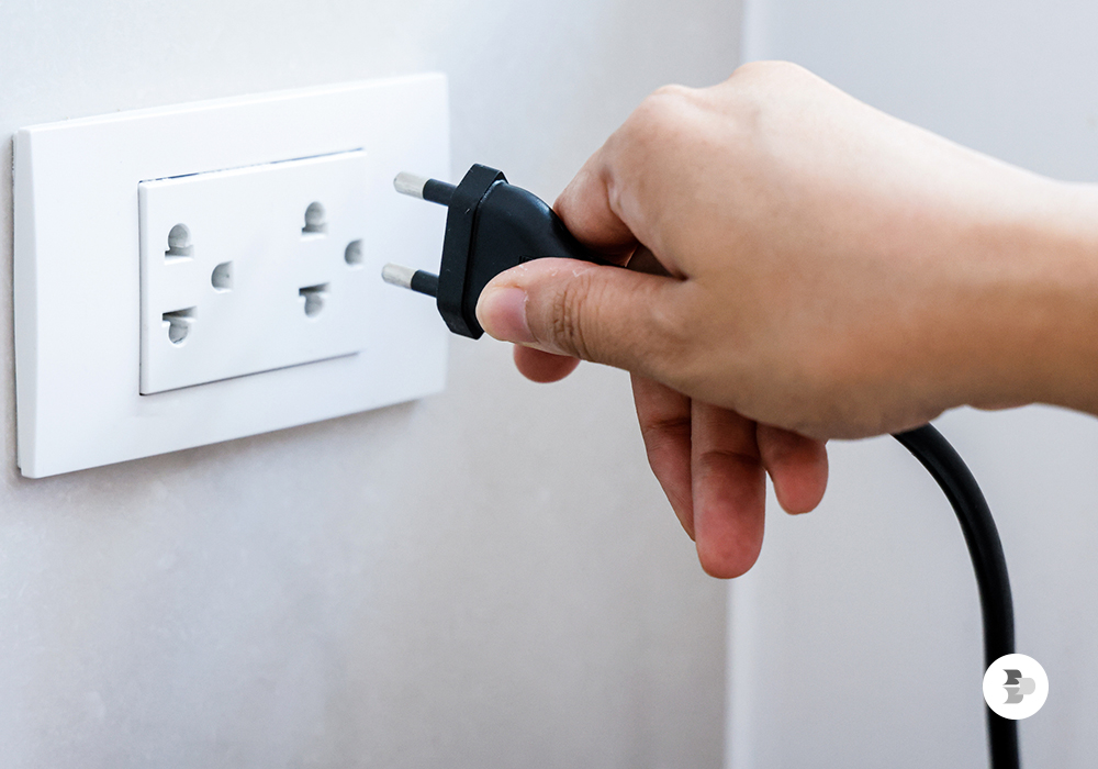 Pessoa ligando um aparelho na tomada. Conta de luz.