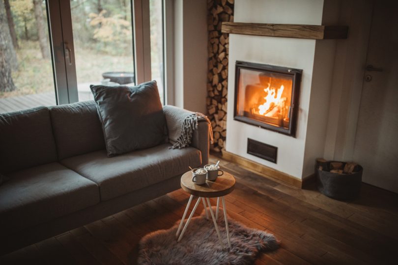 Uma Sala de Estar com lareira e sofá aconchegante. Casa aquecida.