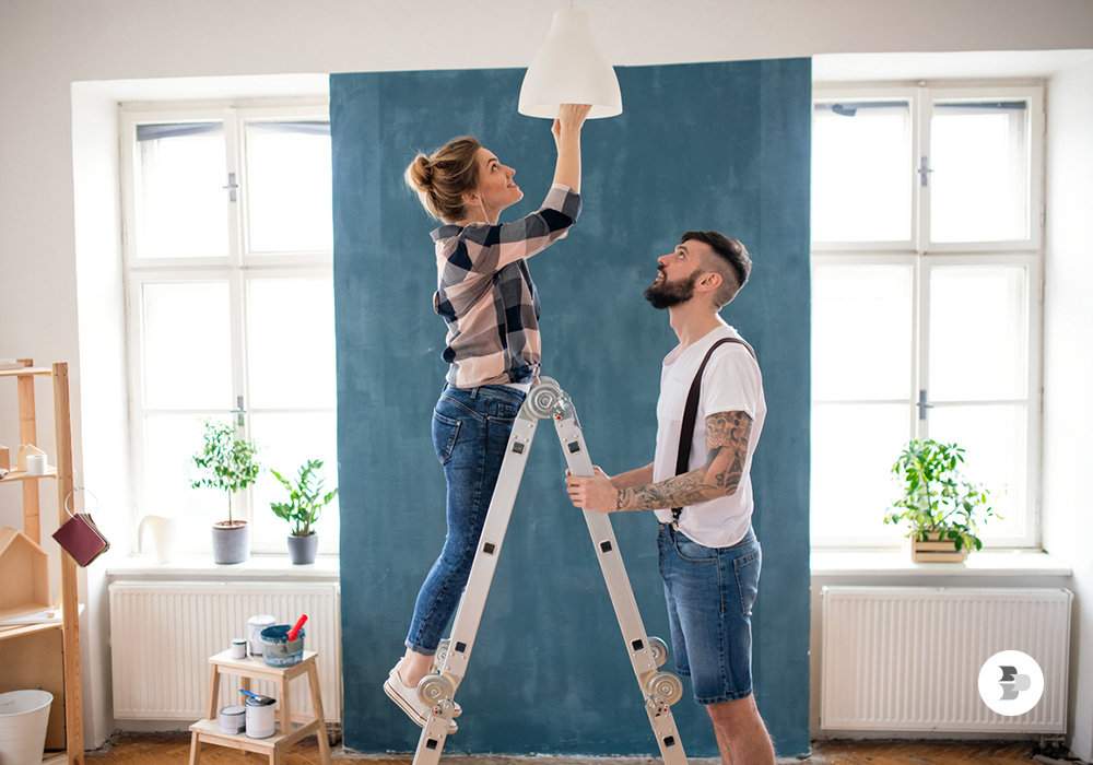 Casal usando a escada para trocar a lâmpada. Escada.