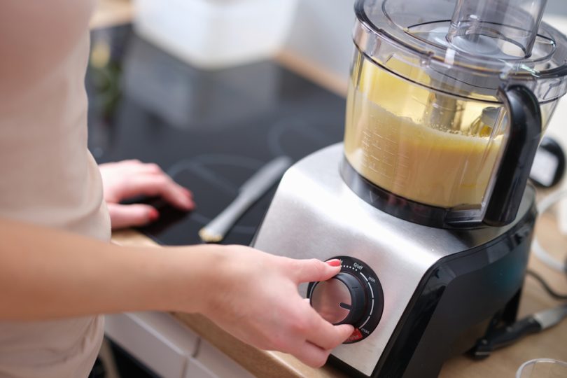 Uma pessoa utilizando o multiprocessador na sua cozinha. Multiprocessador.