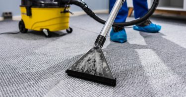 Uma pessoa limpando um tapete com uma extratora. Extratora.