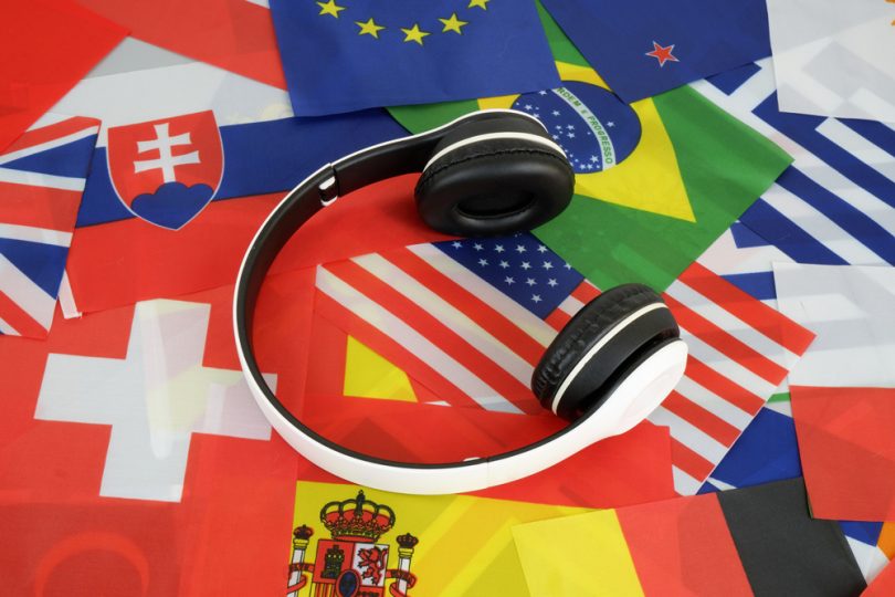Um fone de ouvido com várias bandeiras de países ao redor. Novo idioma.