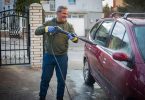 Um homem lavando o seu carro em casa. Lavadora Alta Pressão.