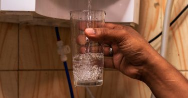 Uma pessoa pegando água de um purificador. Purificador.