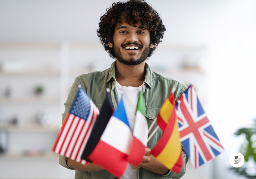 Um rapaz segurando várias bandeiras de países. Idioma.