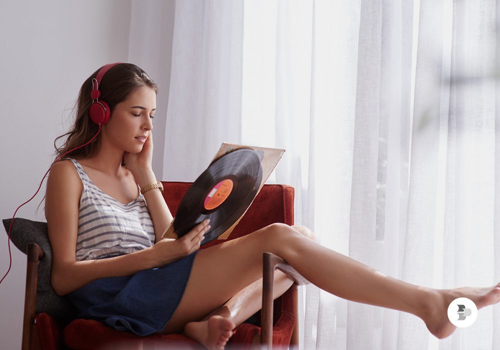 Uma jovem sentada no sofá ouvindo as músicas do disco de vinil. Discos de vinil.