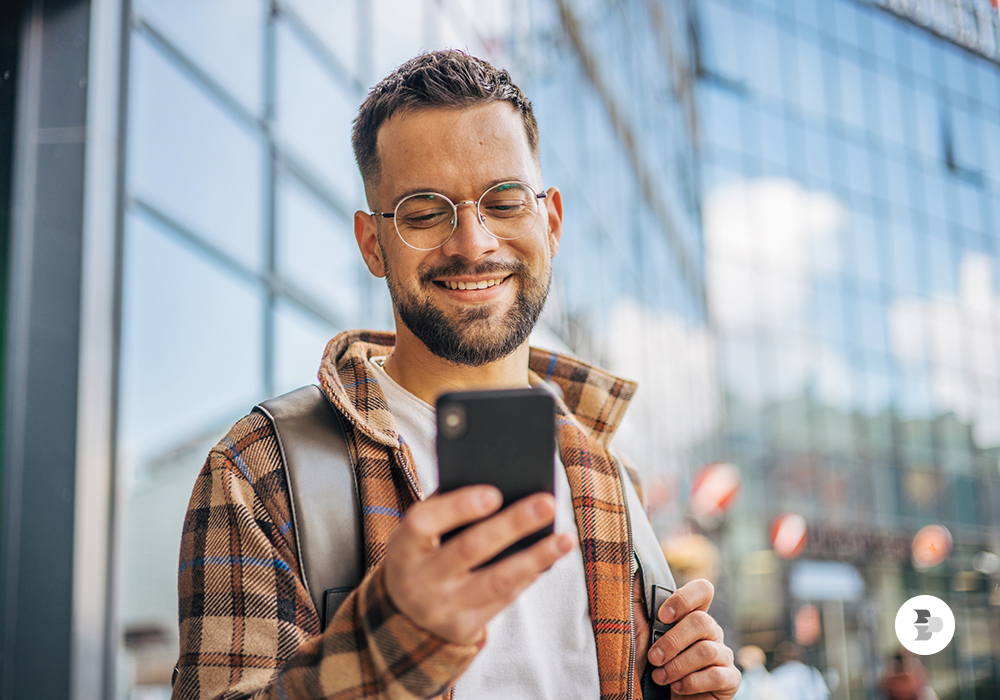 Um jovem utilizando o seu smartphone enquanto está na rua. Smartphones 2025.