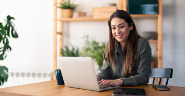 Uma mulher trabalhando com o seu notebook em casa. Bom notebook.