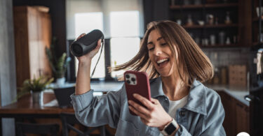 Mulher cantando enquanto segura sua caixa de som. Comprar caixa de som.