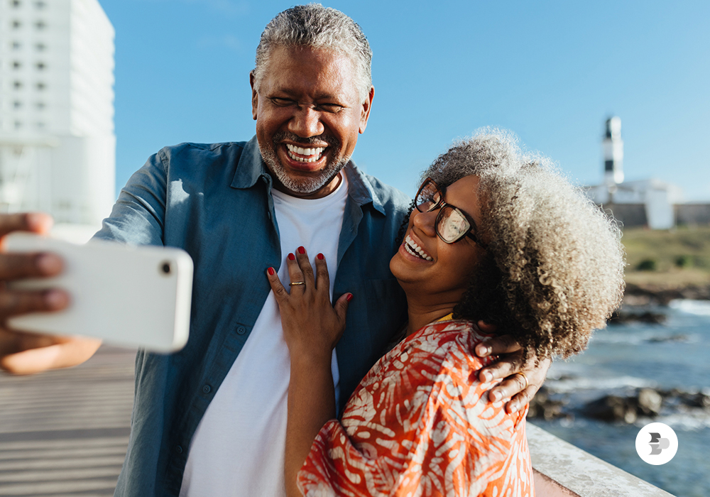 Casal tirando selfies na praia. Escolher smartphone.