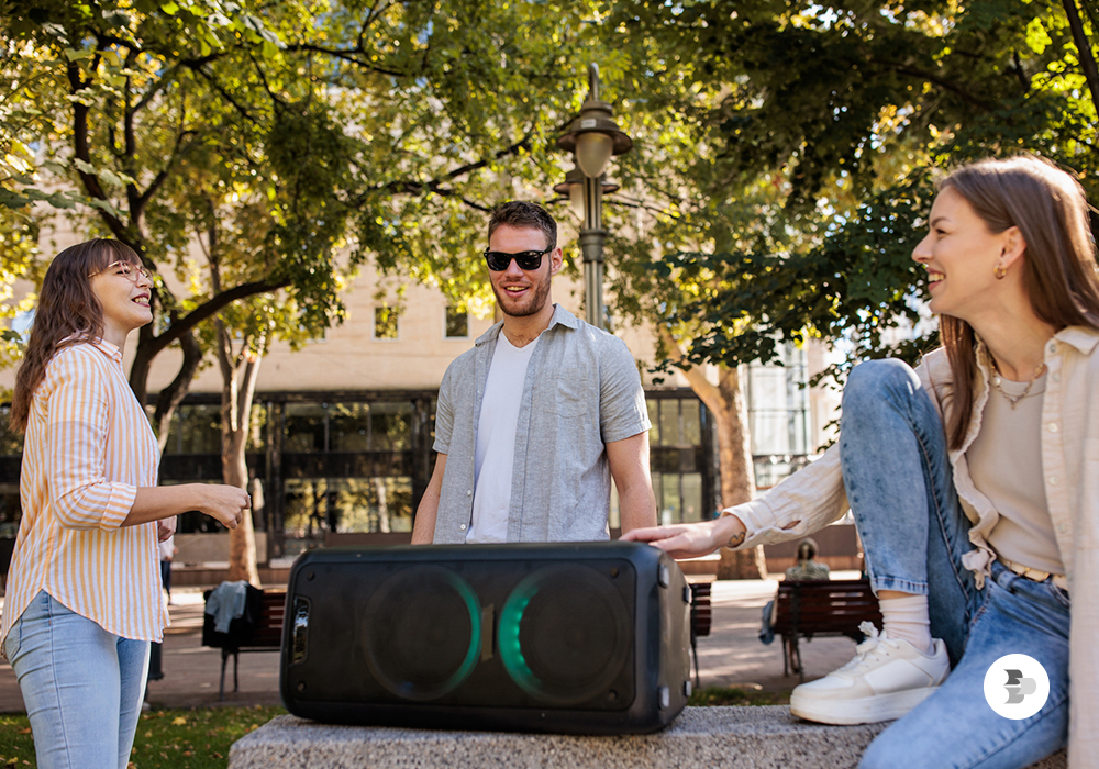 Grupo de amigos escutando música em um parque. Comprar caixa de som.