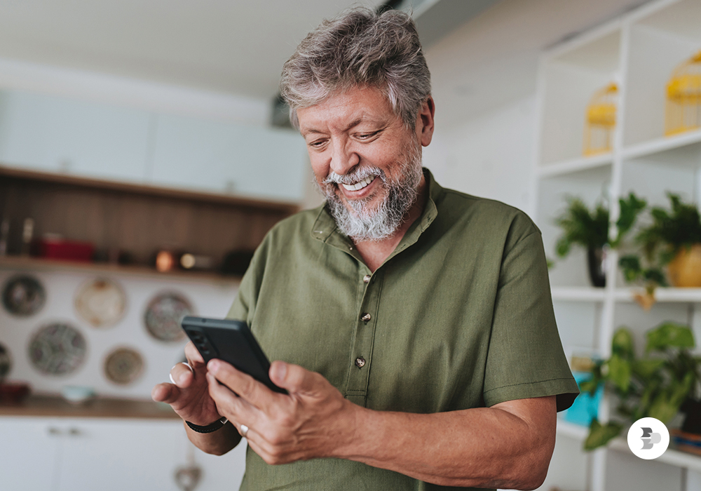Homem de idade usando o seu smartphone em casa. Escolher smartphone.