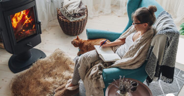 Uma mulher e um gato em um sofá com o calefator funcionando. Calefator.