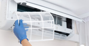 Uma pessoa limpando o filtro do ar-condicionado. Limpeza ar-condicionado.