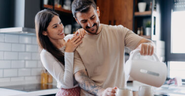 Um casal preparando uma bebida quente com uma jarra elétrica. Jarra elétrica.