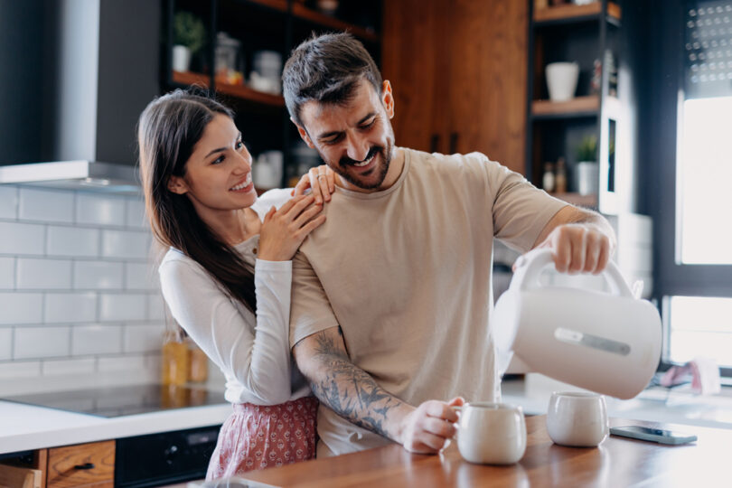 Um casal preparando uma bebida quente com uma jarra elétrica. Jarra elétrica.