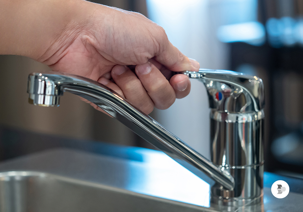 Uma pessoa fecha a torneira da sua pia. Preservar meio ambiente.