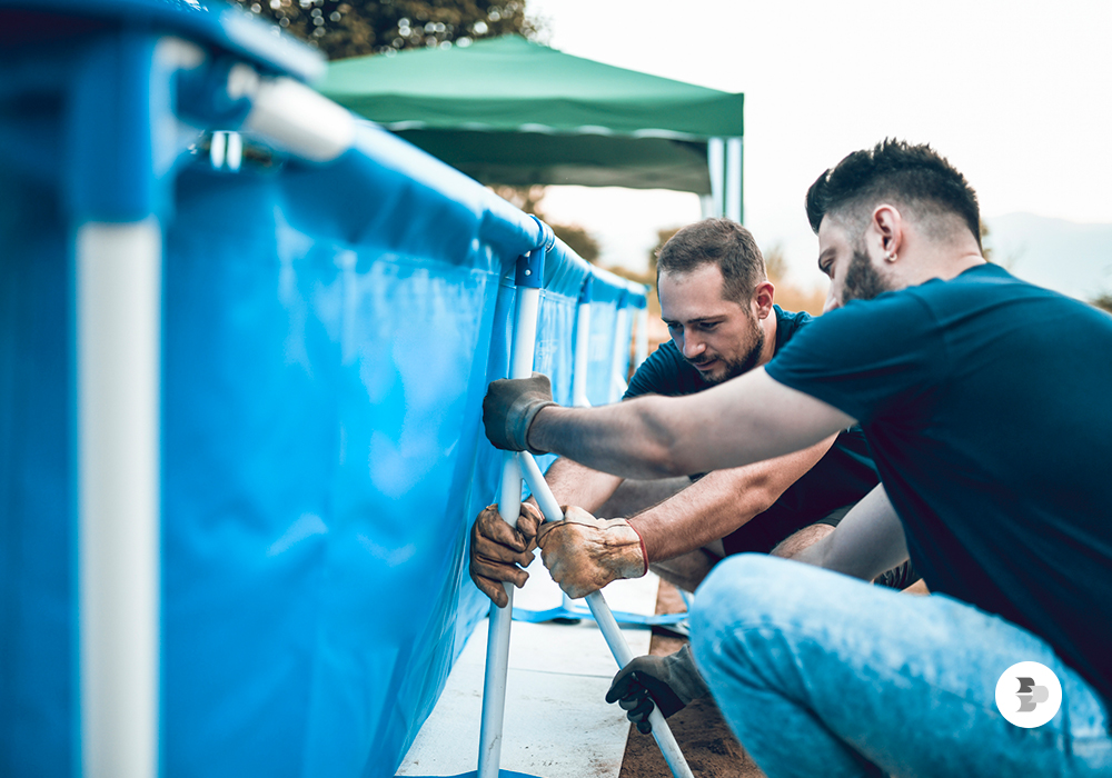 Dois homens montando uma piscina grande desmontável. Piscina grande.