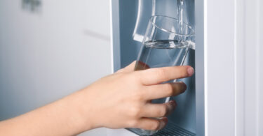 Uma pessoa pegando água para beber. Benefícios purificador de água.