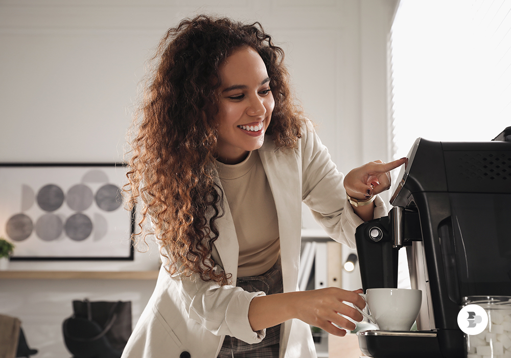 Uma jovem moça preparando seu café em uma cafeteira espresso. Eletroportáteis casa.